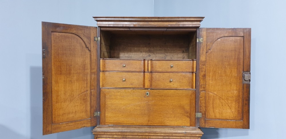A George I walnut secretaire chest of small proportions featuring an upper double cabinet with arched door panels over a base of four drawers with brass hardware. View XIII