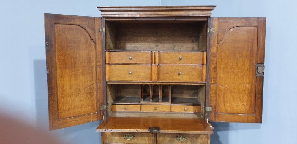 A George I walnut secretaire chest of small proportions featuring an upper double cabinet with arched door panels over a base of four drawers with brass hardware. View XIV