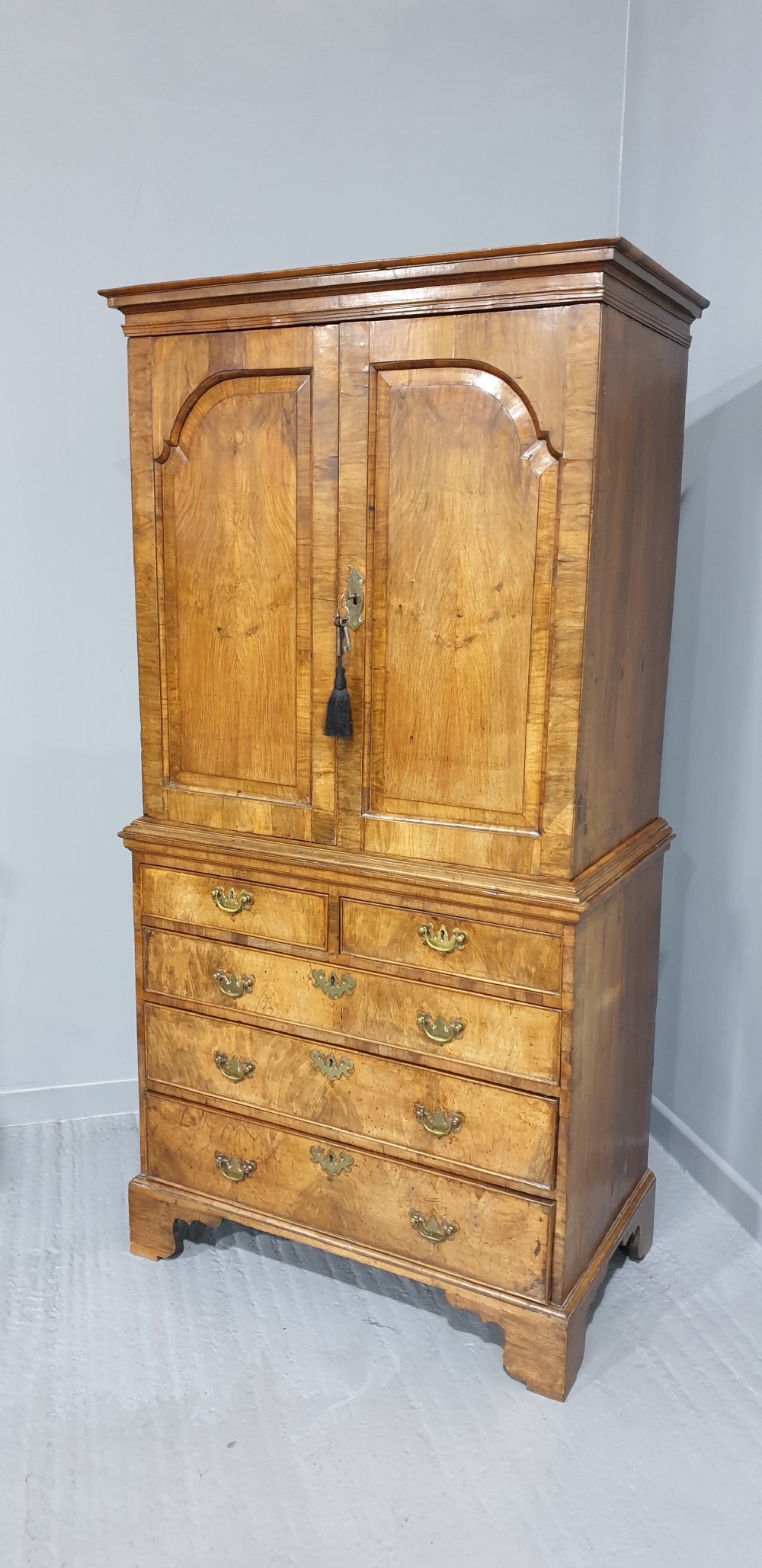A George I walnut secretaire chest of small proportions featuring an upper double cabinet with arched door panels over a base of four drawers with brass hardware. View XX