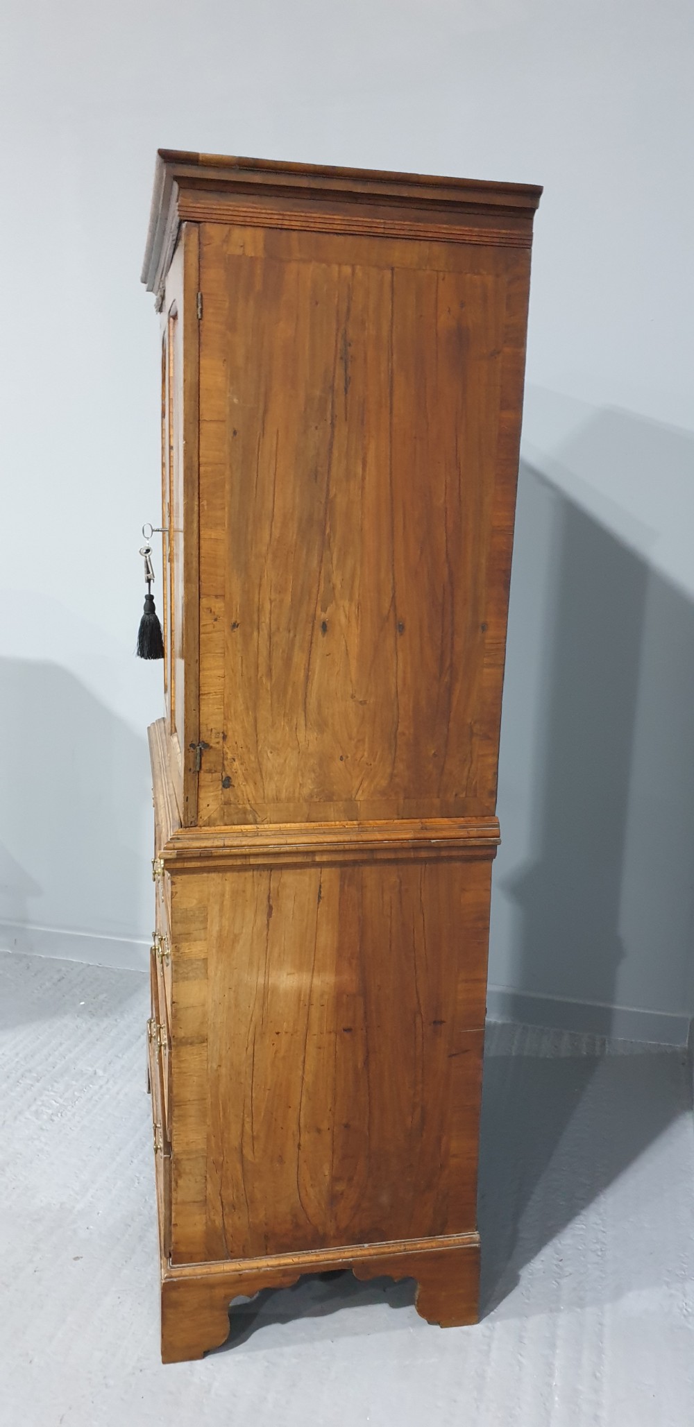A George I walnut secretaire chest of small proportions featuring an upper double cabinet with arched door panels over a base of four drawers with brass hardware. View XXI