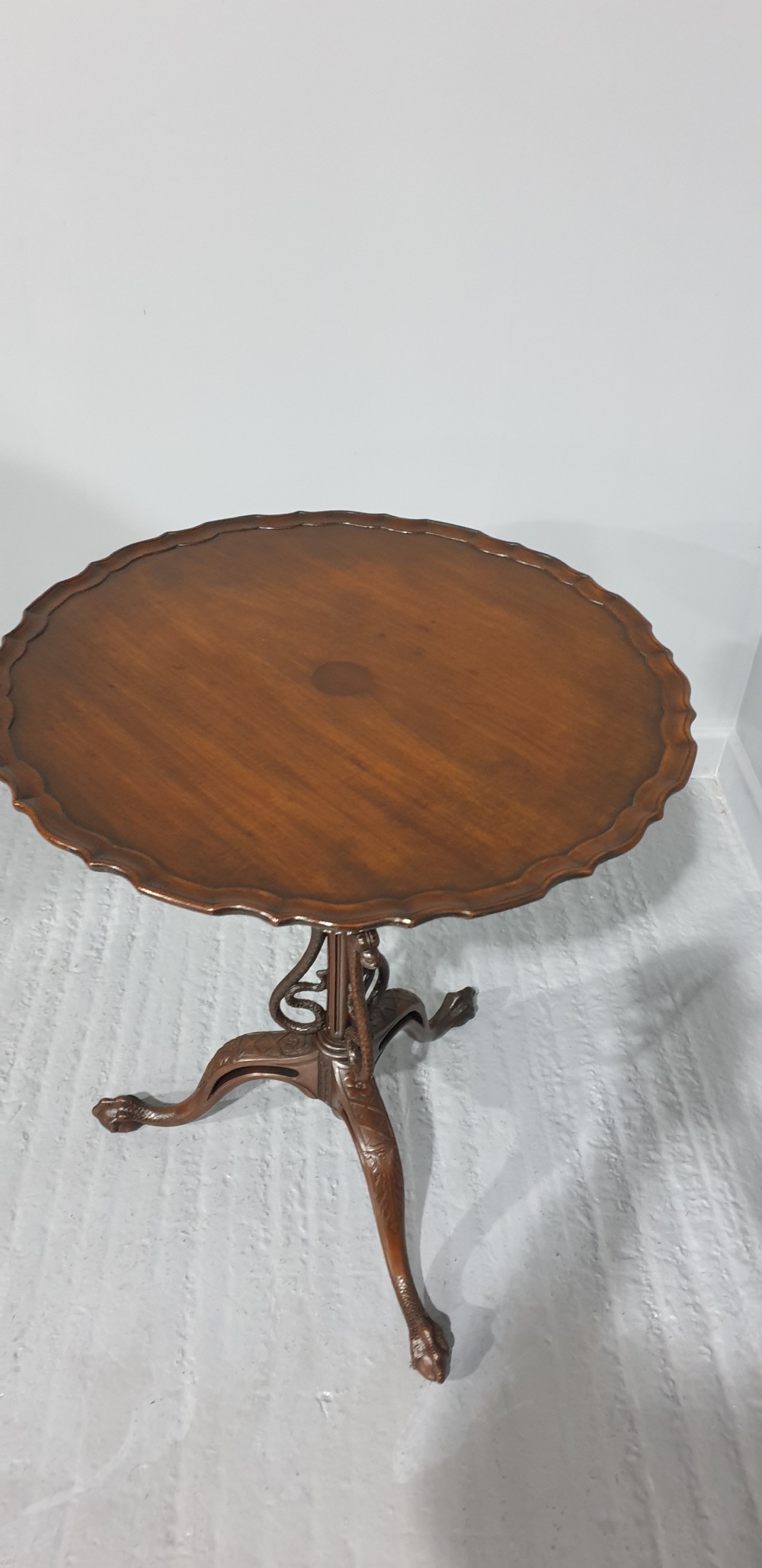 A mahogany tilt-top table with a pie-crust scalloped rim, resting on a carved tripod base with cabriole legs. View II