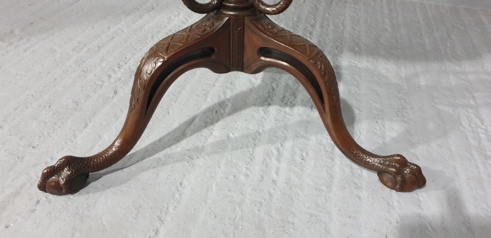 A mahogany tilt-top table with a pie-crust scalloped rim, resting on a carved tripod base with cabriole legs. View III