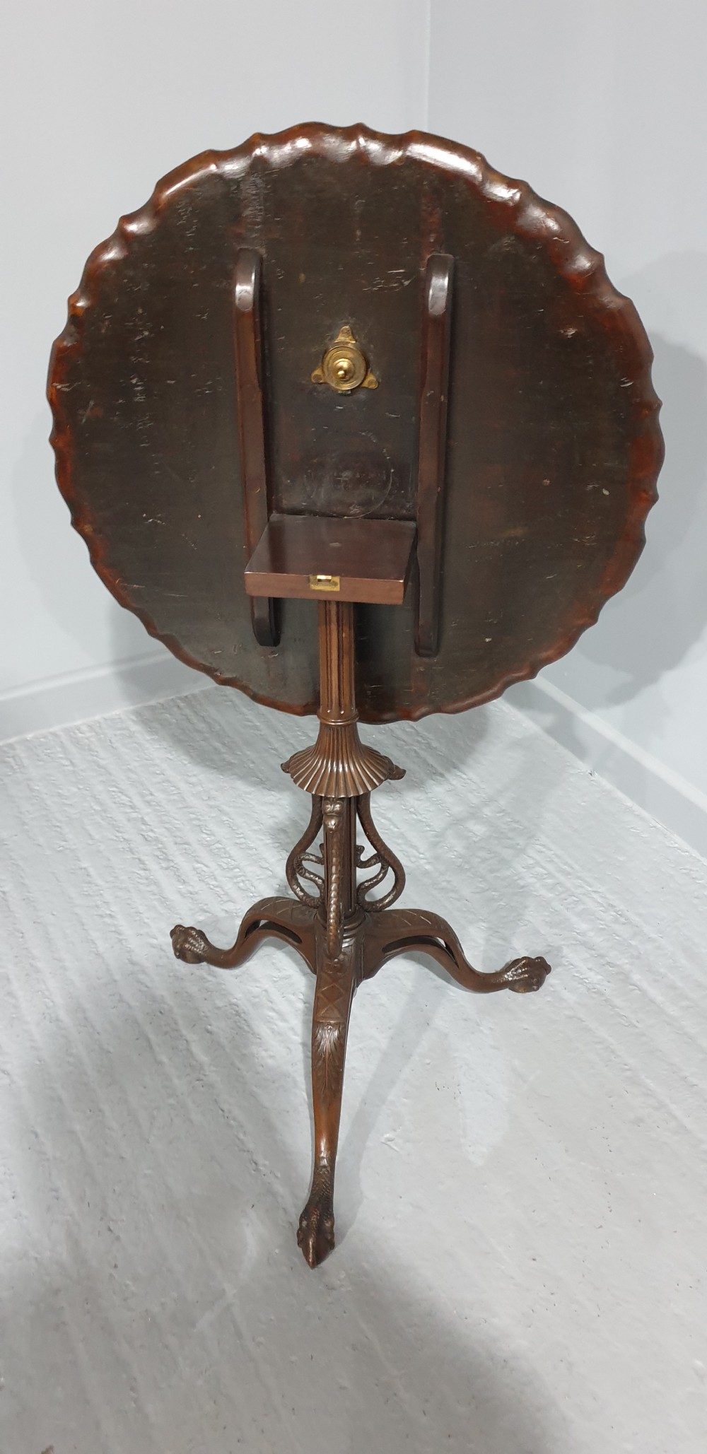 A mahogany tilt-top table with a pie-crust scalloped rim, resting on a carved tripod base with cabriole legs. View VIII