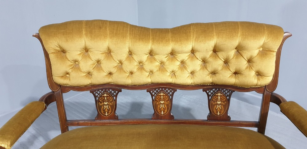 An Edwardian mahogany two-seat settee upholstered in button-tufted gold velvet with decorative marquetry inlays on the backrest and arm supports. View II