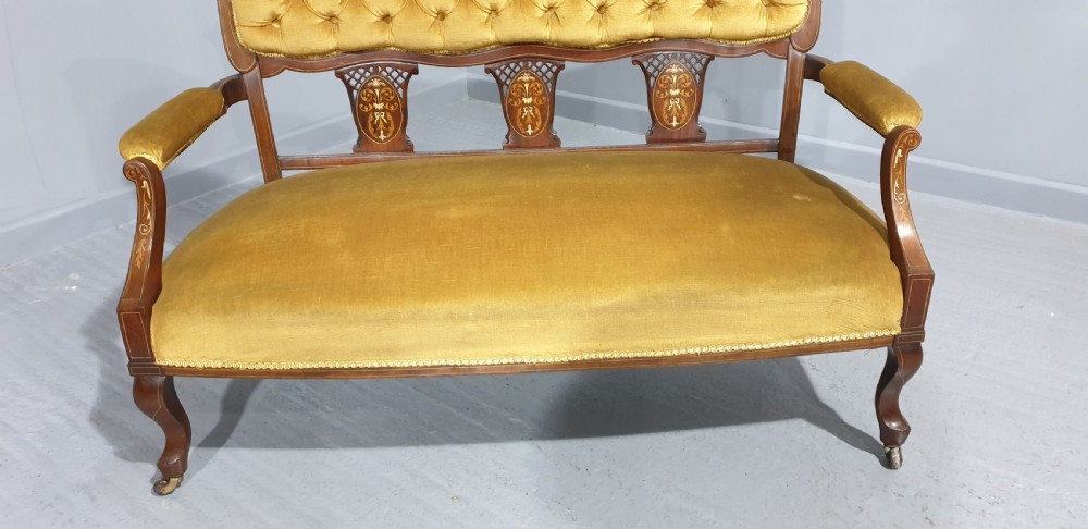 An Edwardian mahogany two-seat settee upholstered in button-tufted gold velvet with decorative marquetry inlays on the backrest and arm supports. View III