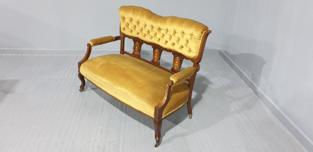 An Edwardian mahogany two-seat settee upholstered in button-tufted gold velvet with decorative marquetry inlays on the backrest and arm supports. View VII