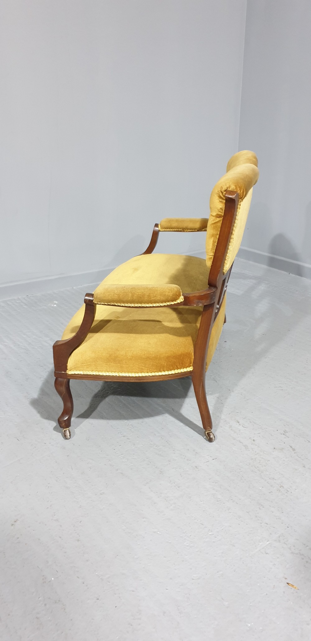 An Edwardian mahogany two-seat settee upholstered in button-tufted gold velvet with decorative marquetry inlays on the backrest and arm supports. View VIII