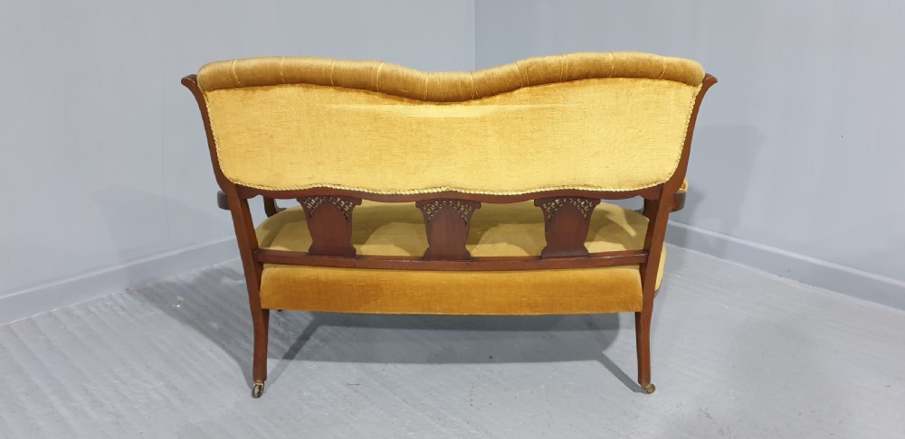 An Edwardian mahogany two-seat settee upholstered in button-tufted gold velvet with decorative marquetry inlays on the backrest and arm supports. View IX
