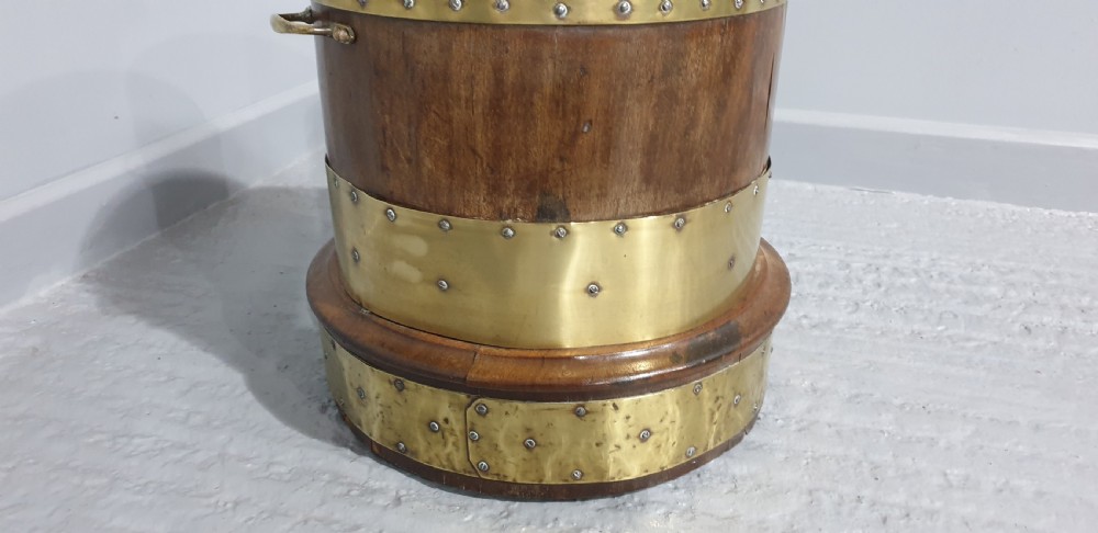 A cylindrical mahogany wood log bin with wide polished brass bands and side carrying handles. View III