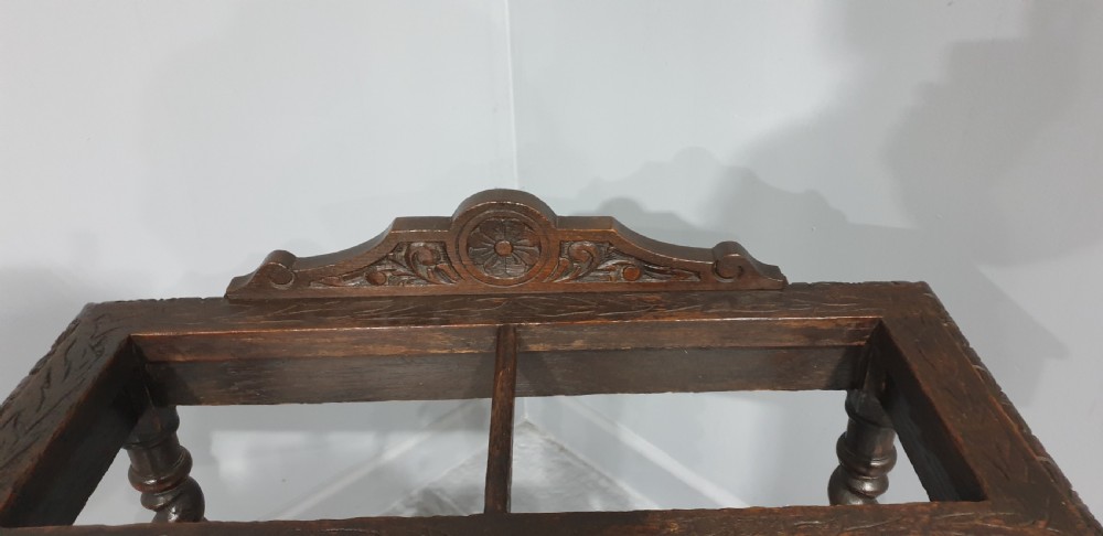 A dark oak stick stand with carved top cresting, barley twist support legs, carved frieze, and lower drip tray. View III