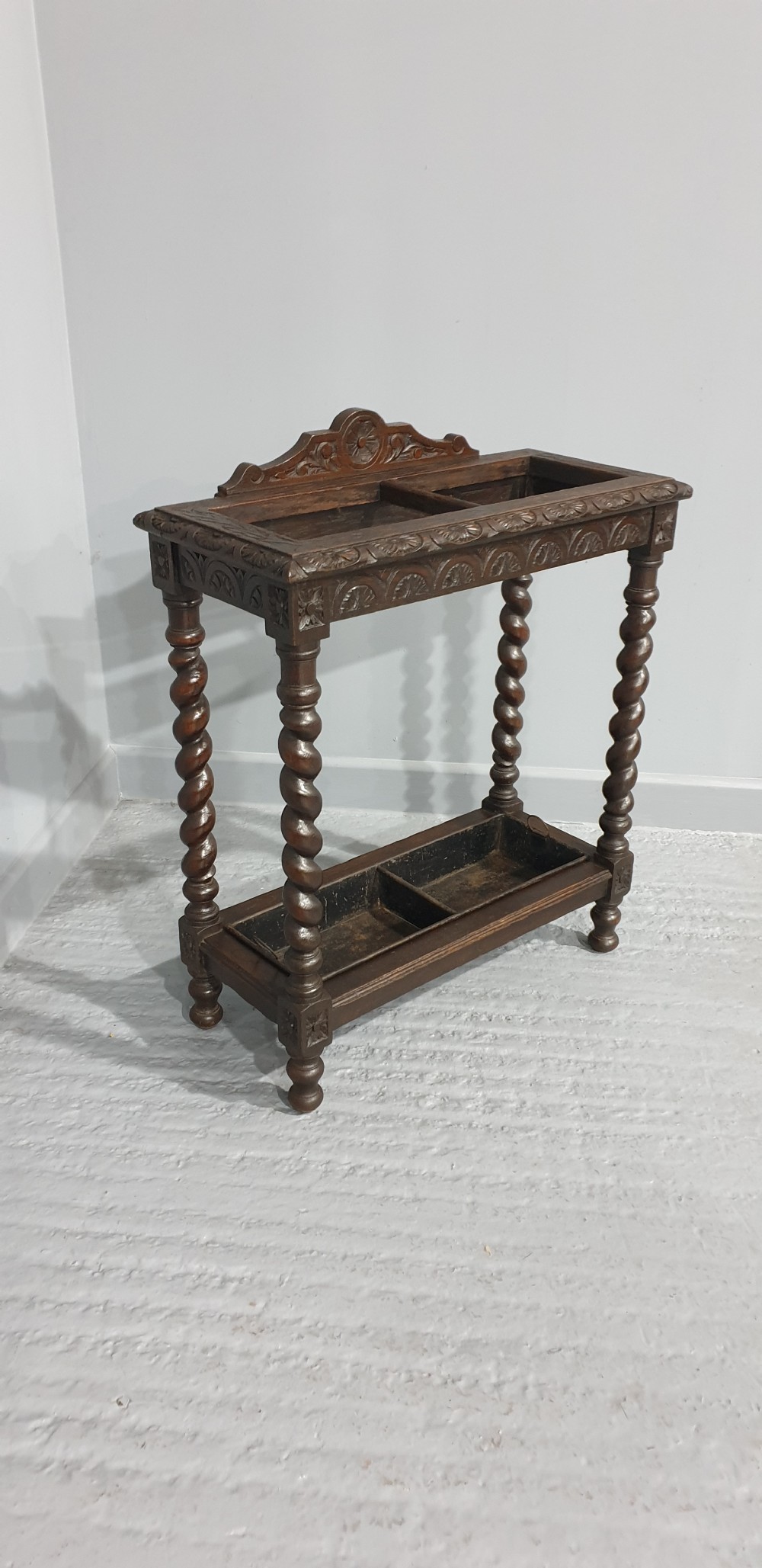 A dark oak stick stand with carved top cresting, barley twist support legs, carved frieze, and lower drip tray. View IV