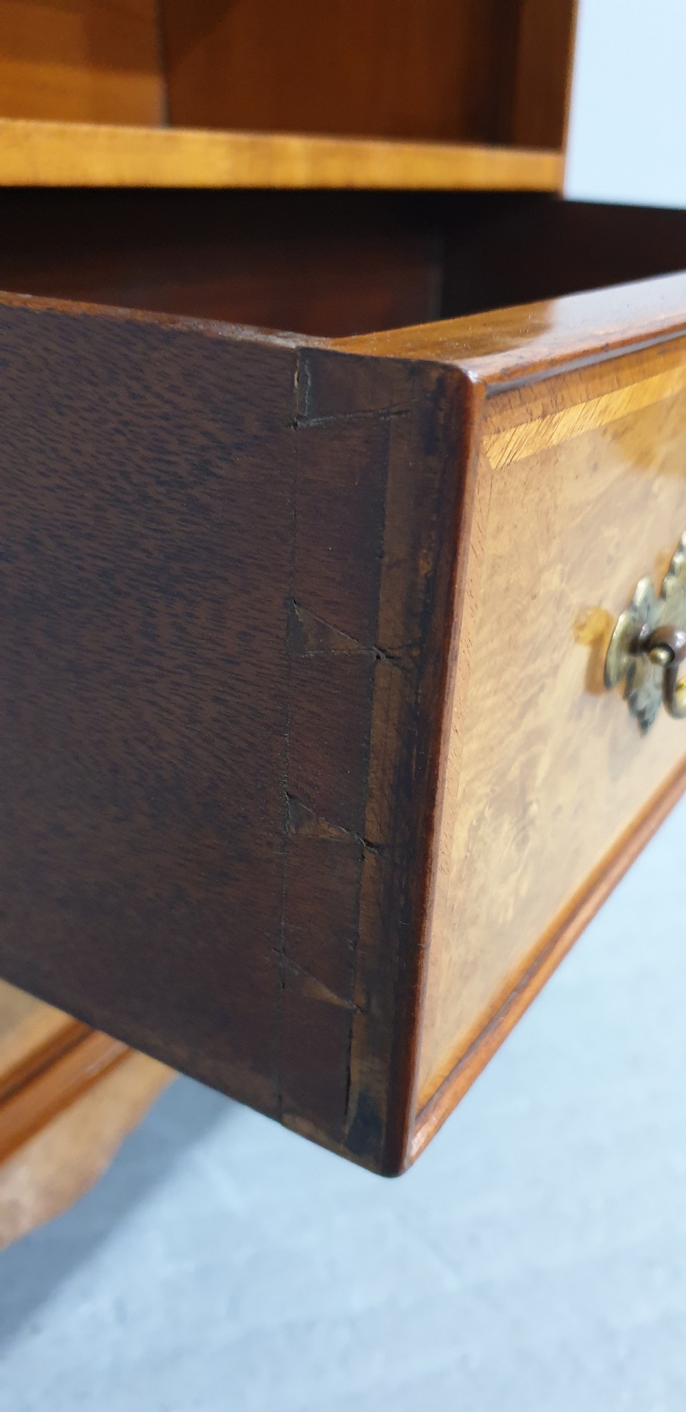 A low burr walnut open bookcase featuring a top shelf filled with leather-bound books, two lower drawers with brass handles, and cabriole legs. View VIII