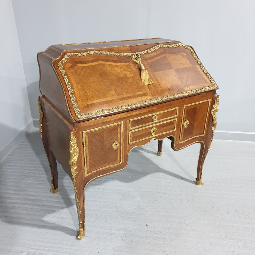 An early nineteenth-century French kingwood parquetry slant-front bureau featuring gilt-bronze ormolu mounts, cabriole legs, and geometric timber inlay.
