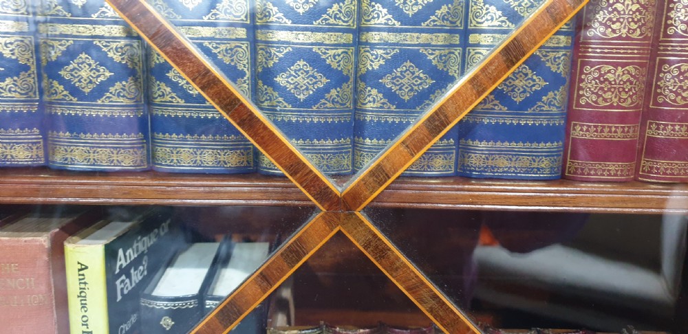 A narrow mahogany standing bookcase featuring a swan-neck pediment top, geometric astragal glazed door, and a lower door with an inlaid oval shell cartouche. View VIII