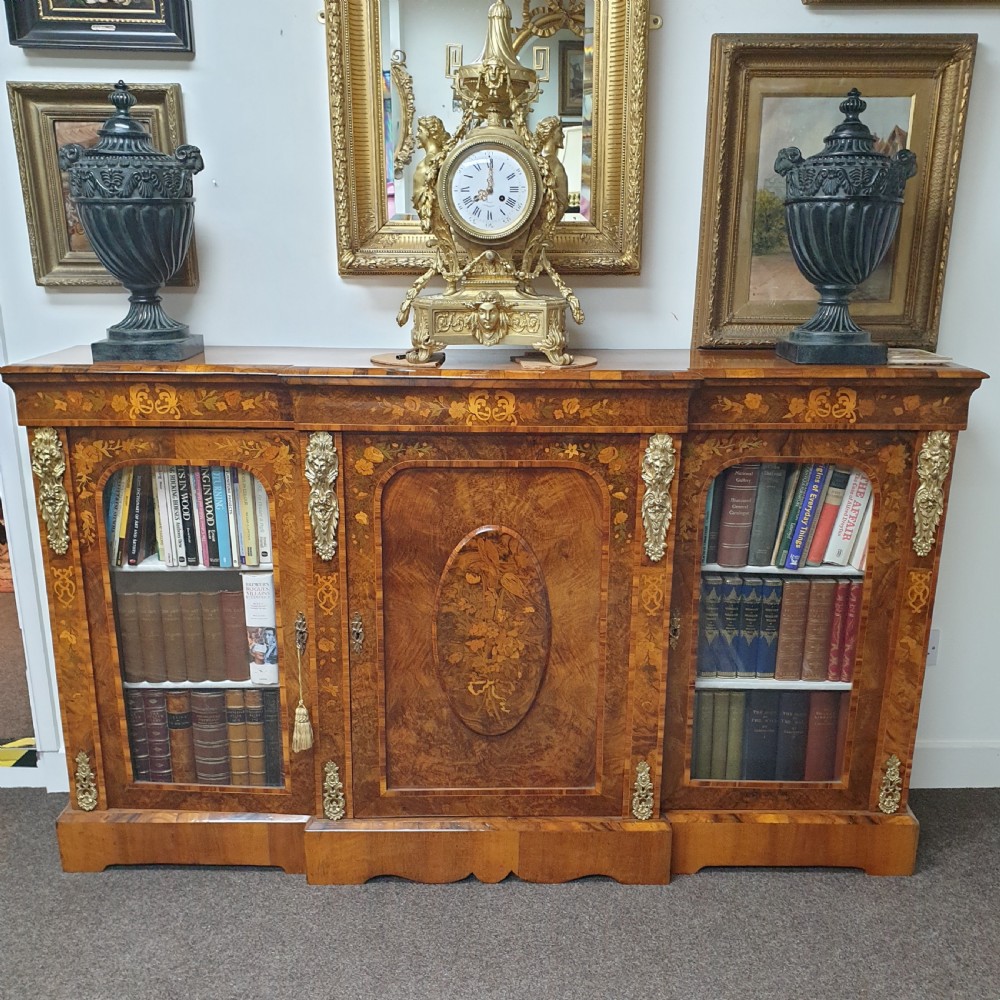 A low burr walnut and floral marquetry credenza bookcase featuring glazed side doors, a central solid panel door, and ornamental gilt-bronze mounts.