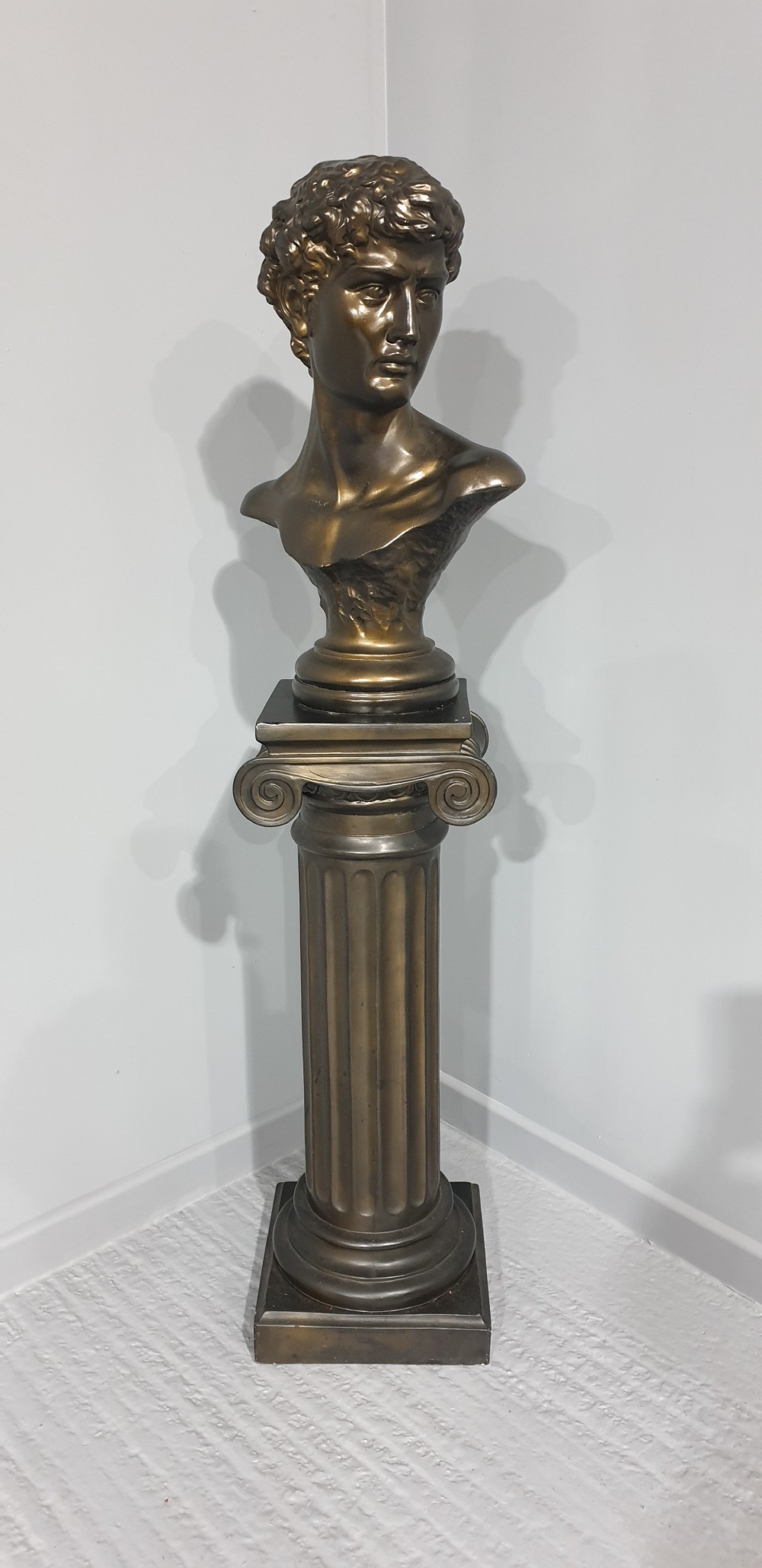 A bronze-patinated plaster bust depicting Michelangelos David mounted on a matching fluted Ionic column pedestal. View II