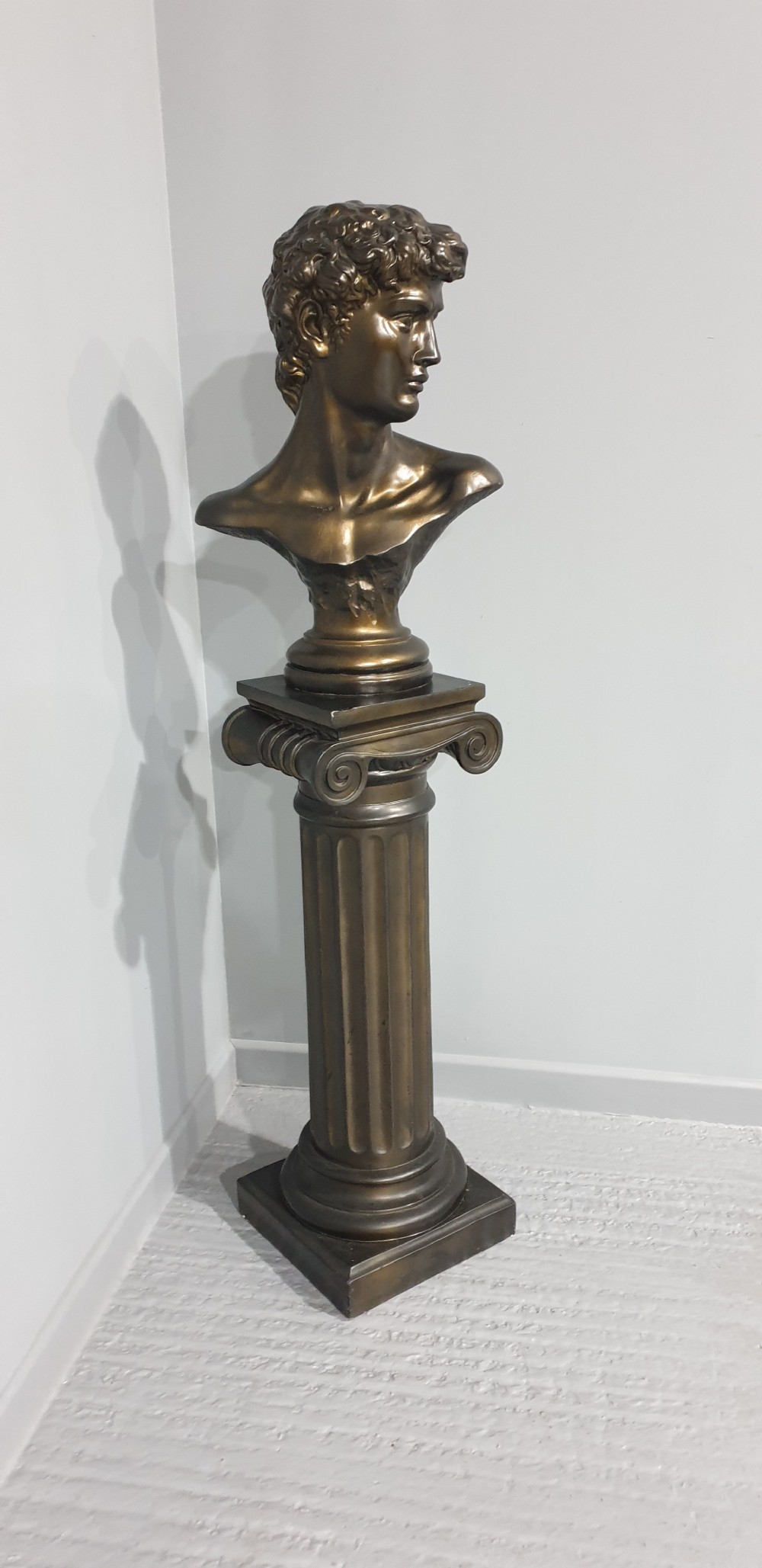 A bronze-patinated plaster bust depicting Michelangelos David mounted on a matching fluted Ionic column pedestal. View III