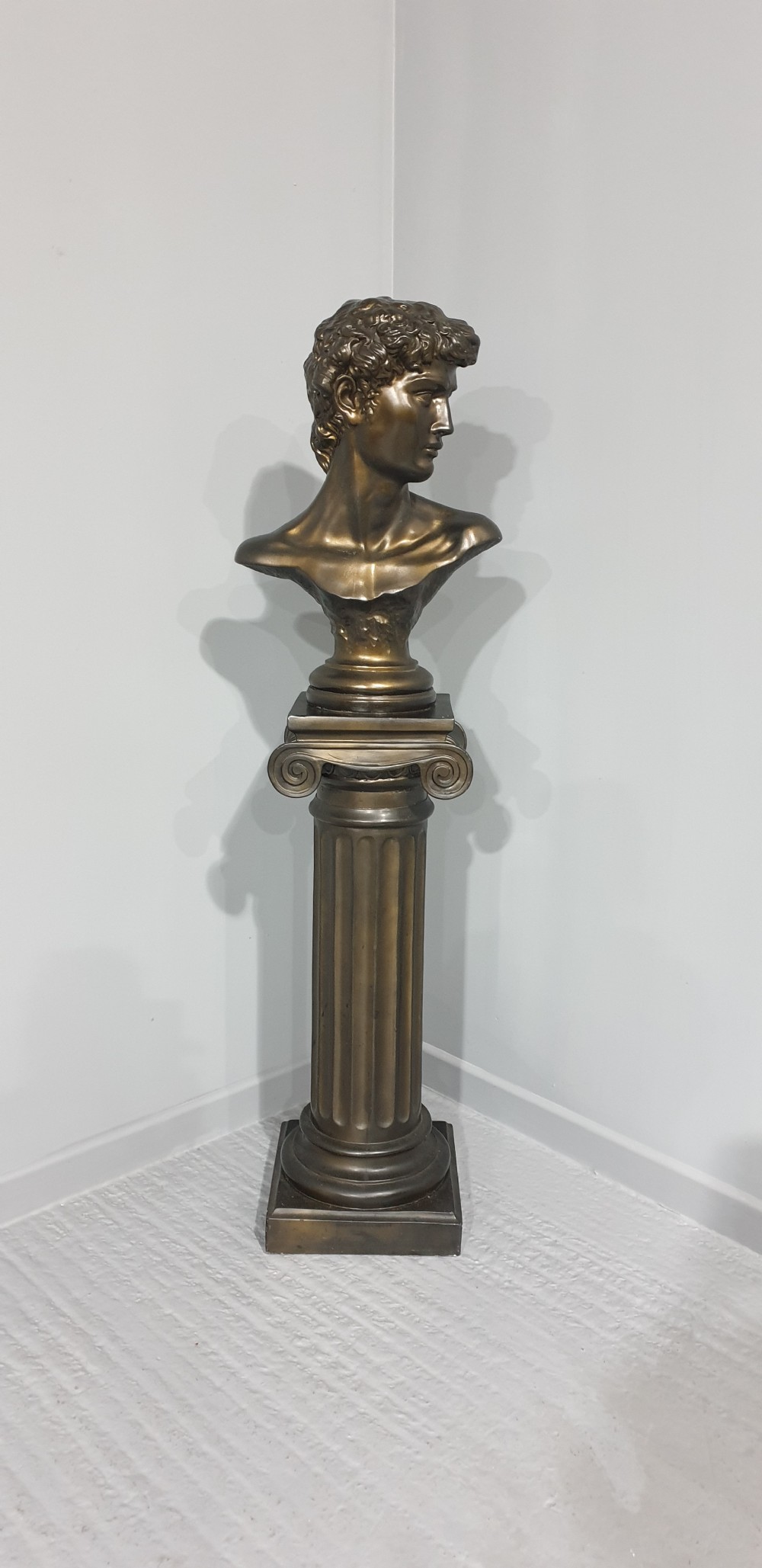 A bronze-patinated plaster bust depicting Michelangelos David mounted on a matching fluted Ionic column pedestal. View V