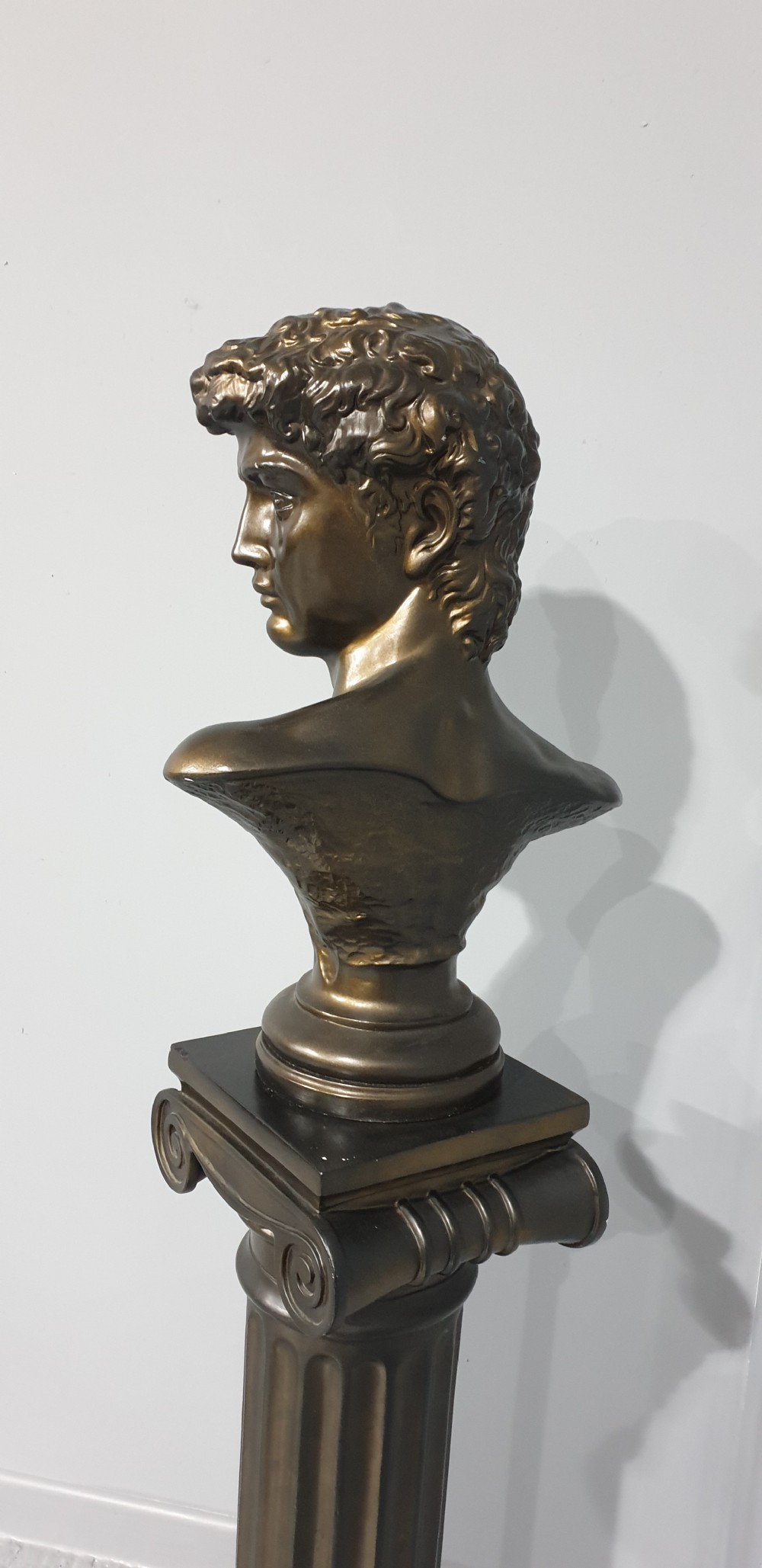 A bronze-patinated plaster bust depicting Michelangelos David mounted on a matching fluted Ionic column pedestal. View VIII