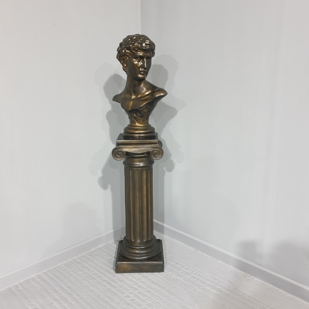 A bronze-patinated plaster bust depicting Michelangelos David mounted on a matching fluted Ionic column pedestal.