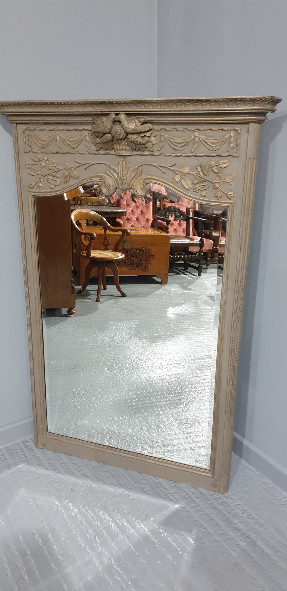 A French grey painted overmantel mirror featuring a carved dove frieze, floral swags, and an arched gilded frame. View II