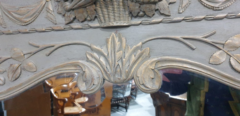A French grey painted overmantel mirror featuring a carved dove frieze, floral swags, and an arched gilded frame. View VI
