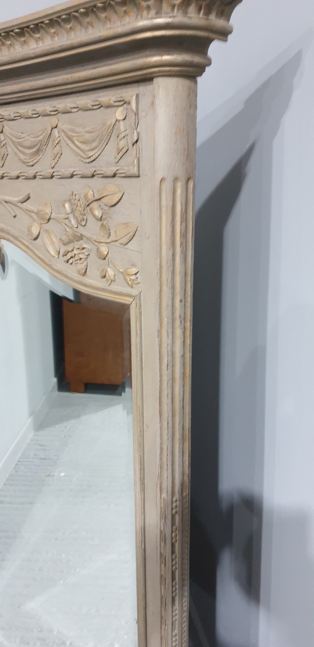 A French grey painted overmantel mirror featuring a carved dove frieze, floral swags, and an arched gilded frame. View VII
