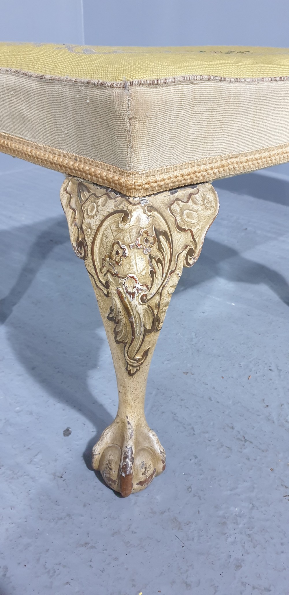 A low rectangular antique stool featuring cream painted cabriole legs with carved knees, ball and claw feet, and a yellow floral needlepoint seat. View IV