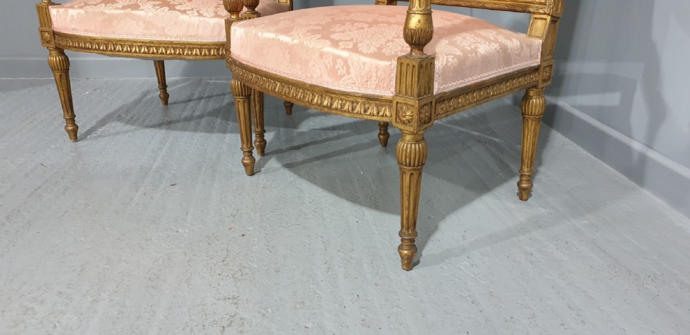 A pair of French Louis XVI style giltwood fauteuil armchairs with fluted legs, carved crests, and pink damask pattern upholstery. View IV