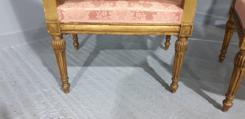 A pair of French Louis XVI style giltwood fauteuil armchairs with fluted legs, carved crests, and pink damask pattern upholstery. View VIII