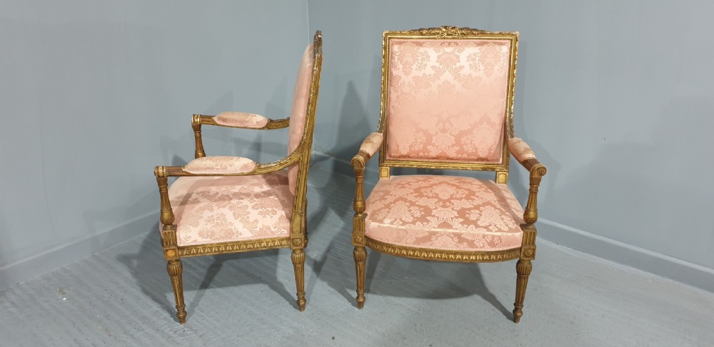 A pair of French Louis XVI style giltwood fauteuil armchairs with fluted legs, carved crests, and pink damask pattern upholstery. View IX