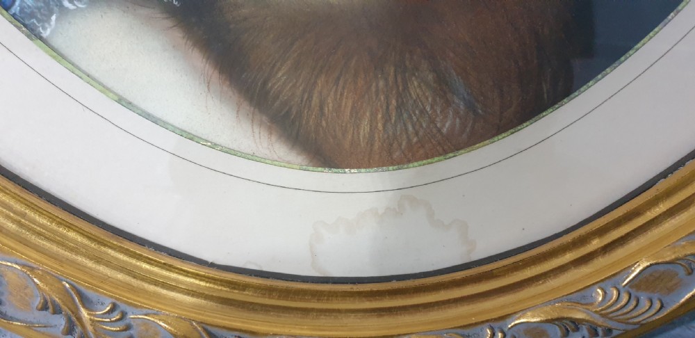 An antique oval Victorian portrait depicting a young girl in a blue dress holding a small dog, set within a carved gold gilded frame. View V