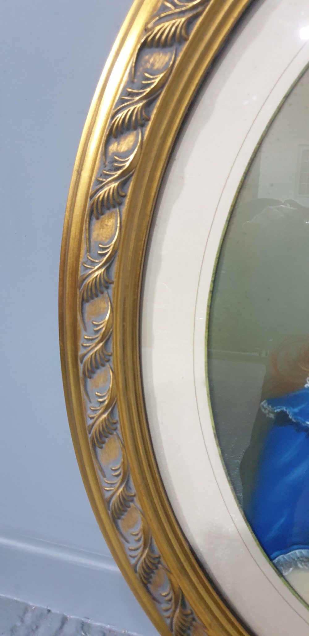 An antique oval Victorian portrait depicting a young girl in a blue dress holding a small dog, set within a carved gold gilded frame. View VII