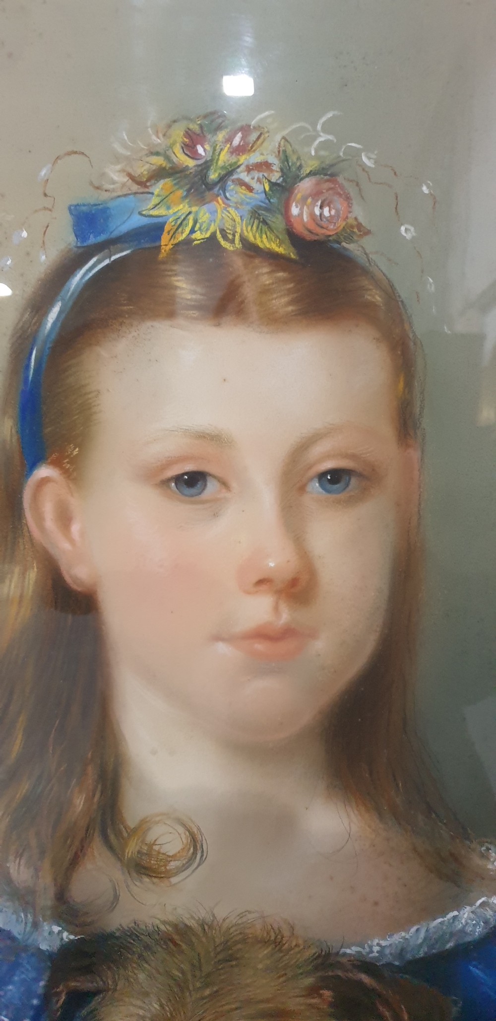 An antique oval Victorian portrait depicting a young girl in a blue dress holding a small dog, set within a carved gold gilded frame. View IX