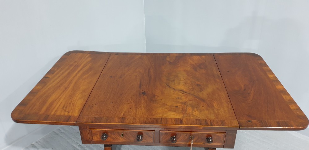 An 18th-century mahogany drop-leaf sofa table with two frieze drawers, crossbanded inlay, sabre legs, and brass castors. View VI