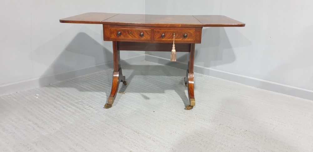 An 18th-century mahogany drop-leaf sofa table with two frieze drawers, crossbanded inlay, sabre legs, and brass castors. View IX