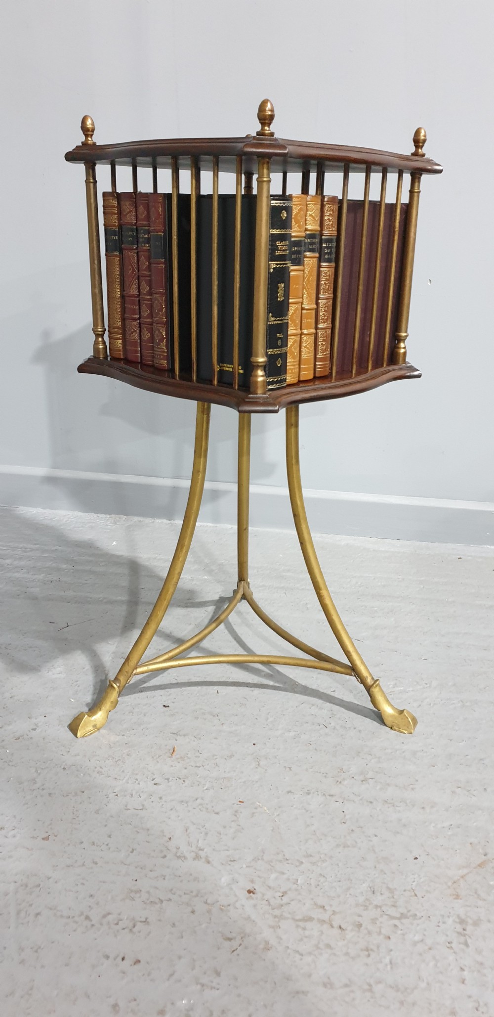 A small square revolving mahogany bookstand featuring brass vertical spindles, corner finials, and a tall tripod brass base with claw feet. View II