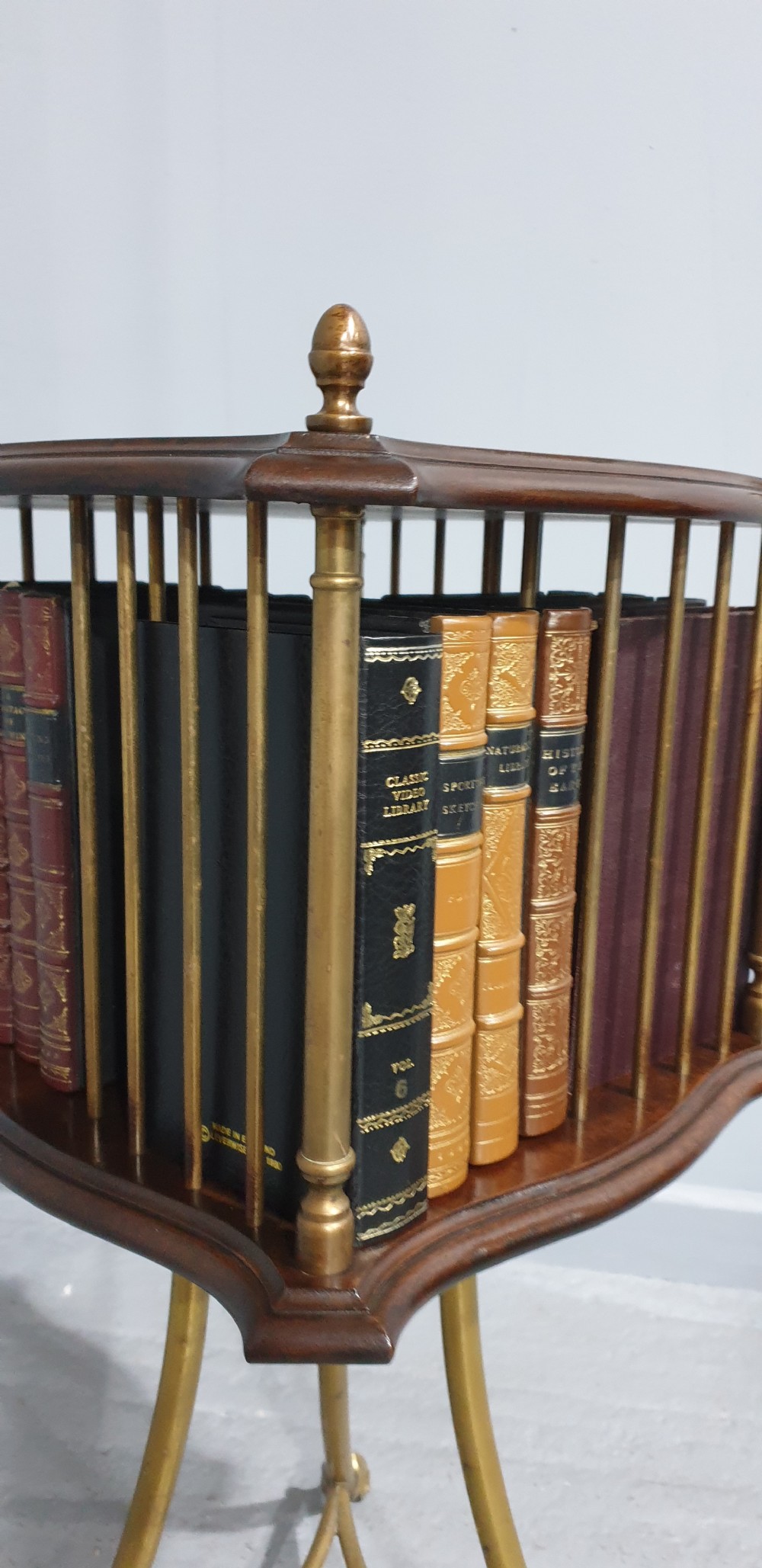 A small square revolving mahogany bookstand featuring brass vertical spindles, corner finials, and a tall tripod brass base with claw feet. View V