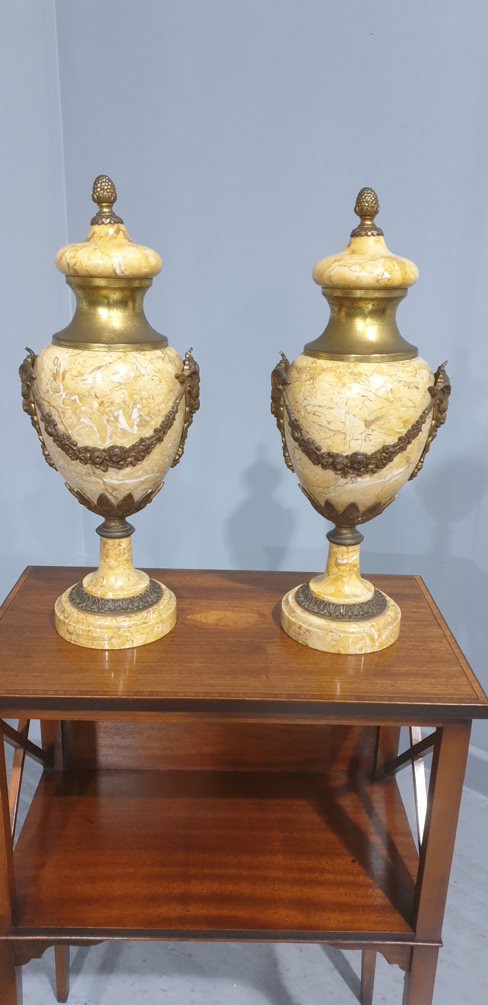 A pair of yellow veined marble cassolette urns with gilt bronze floral swags and pineapple finials.