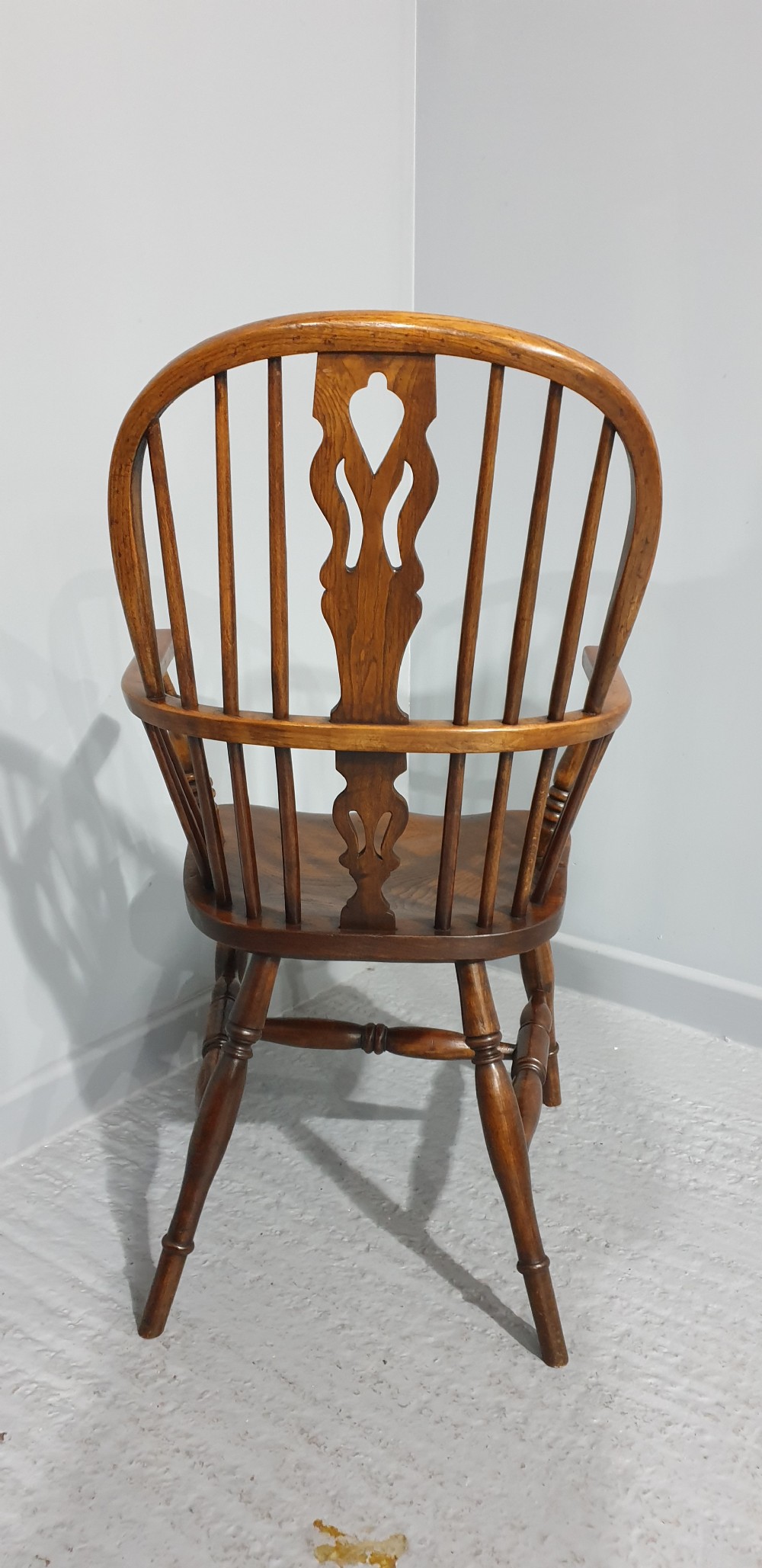 A traditional ash and elm Windsor armchair featuring a hoop back, central pierced splat, turned spindles, and a contoured wooden seat. View VII