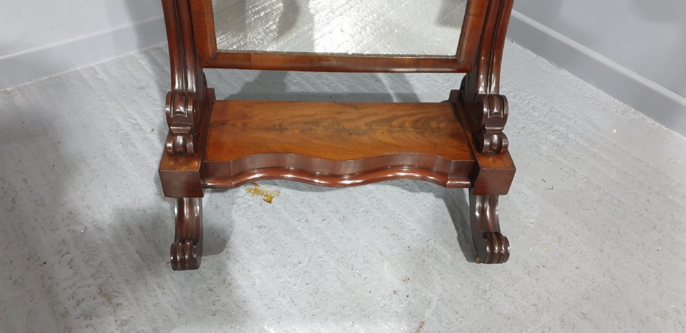 A Victorian mahogany freestanding cheval mirror featuring a rounded rectangular tilting frame on carved scroll legs and a plinth base. View V