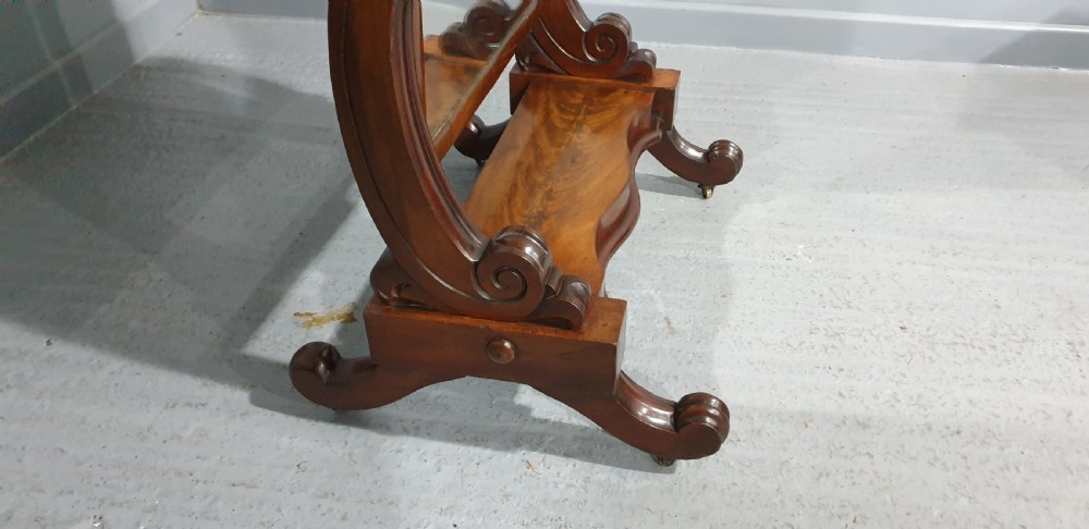 A Victorian mahogany freestanding cheval mirror featuring a rounded rectangular tilting frame on carved scroll legs and a plinth base. View VI