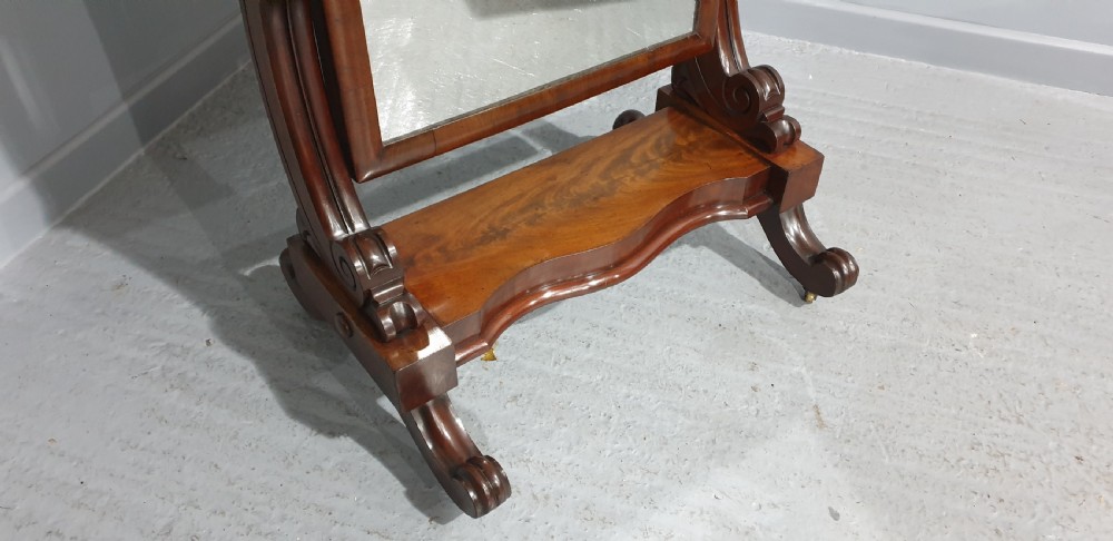 A Victorian mahogany freestanding cheval mirror featuring a rounded rectangular tilting frame on carved scroll legs and a plinth base. View VII