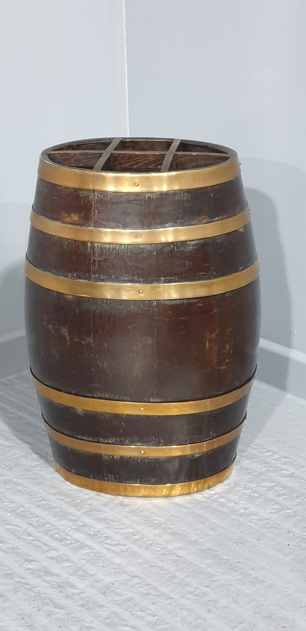 A dark oak barrel stick stand bound with brass hoops and featuring internal grid dividers at the top. View II