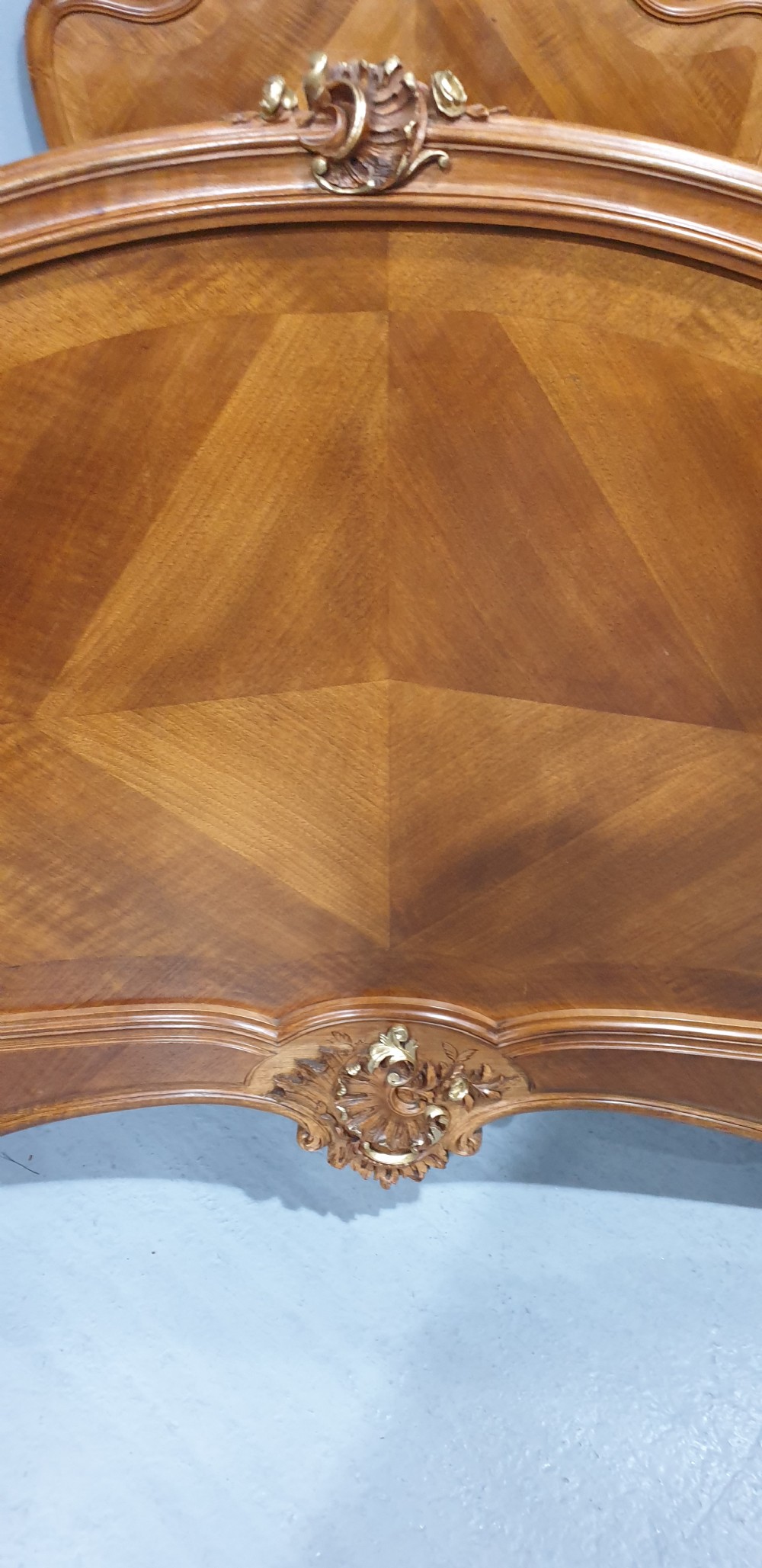 A French Louis XV style walnut bed frame featuring quarter-matched veneered panels and parcel gilt hand-carved cresting on the headboard and footboard. View III