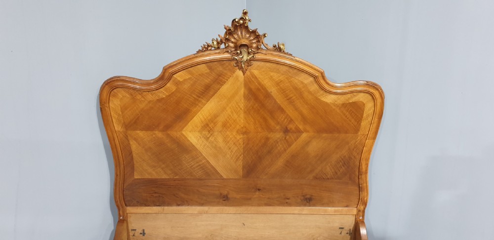 A French Louis XV style walnut bed frame featuring quarter-matched veneered panels and parcel gilt hand-carved cresting on the headboard and footboard. View VI