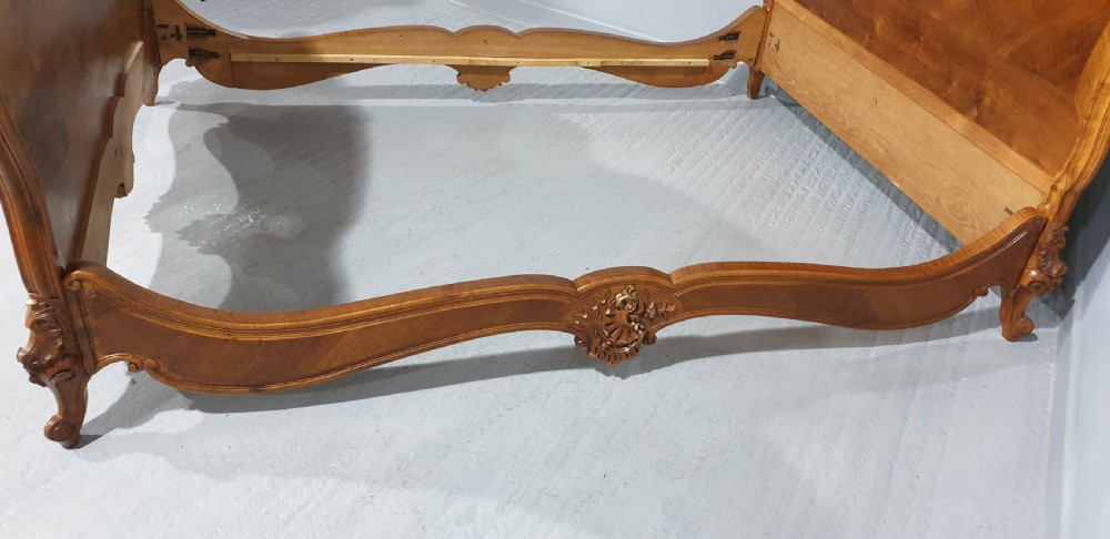 A French Louis XV style walnut bed frame featuring quarter-matched veneered panels and parcel gilt hand-carved cresting on the headboard and footboard. View VIII