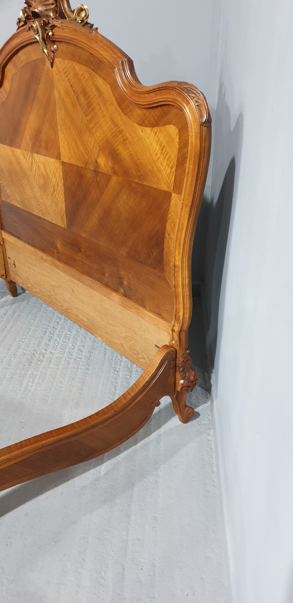 A French Louis XV style walnut bed frame featuring quarter-matched veneered panels and parcel gilt hand-carved cresting on the headboard and footboard. View X