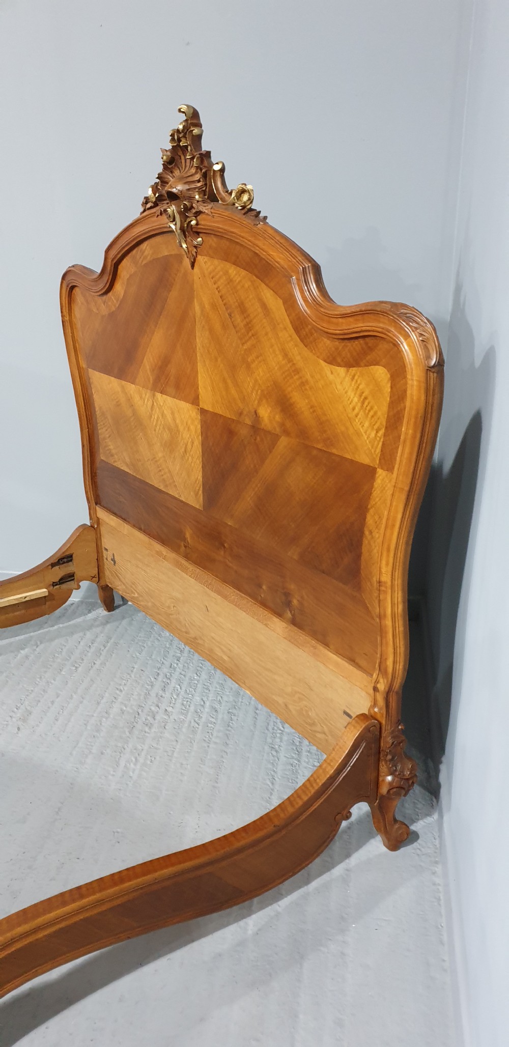 A French Louis XV style walnut bed frame featuring quarter-matched veneered panels and parcel gilt hand-carved cresting on the headboard and footboard. View XI