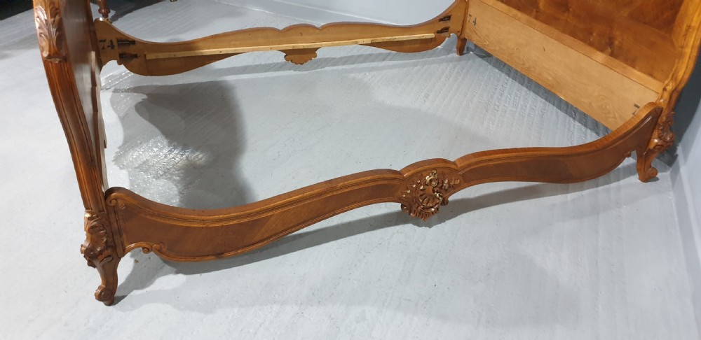 A French Louis XV style walnut bed frame featuring quarter-matched veneered panels and parcel gilt hand-carved cresting on the headboard and footboard. View XII